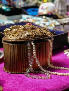 Antique jewelry box adorned with pearls and beads displayed on a vibrant tablecloth, exuding elegance.