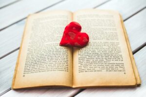 A red heart rests in an open vintage book, evoking romance.