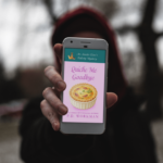 silhouetted figure holding phone with Quiche Me Goodbye on screen