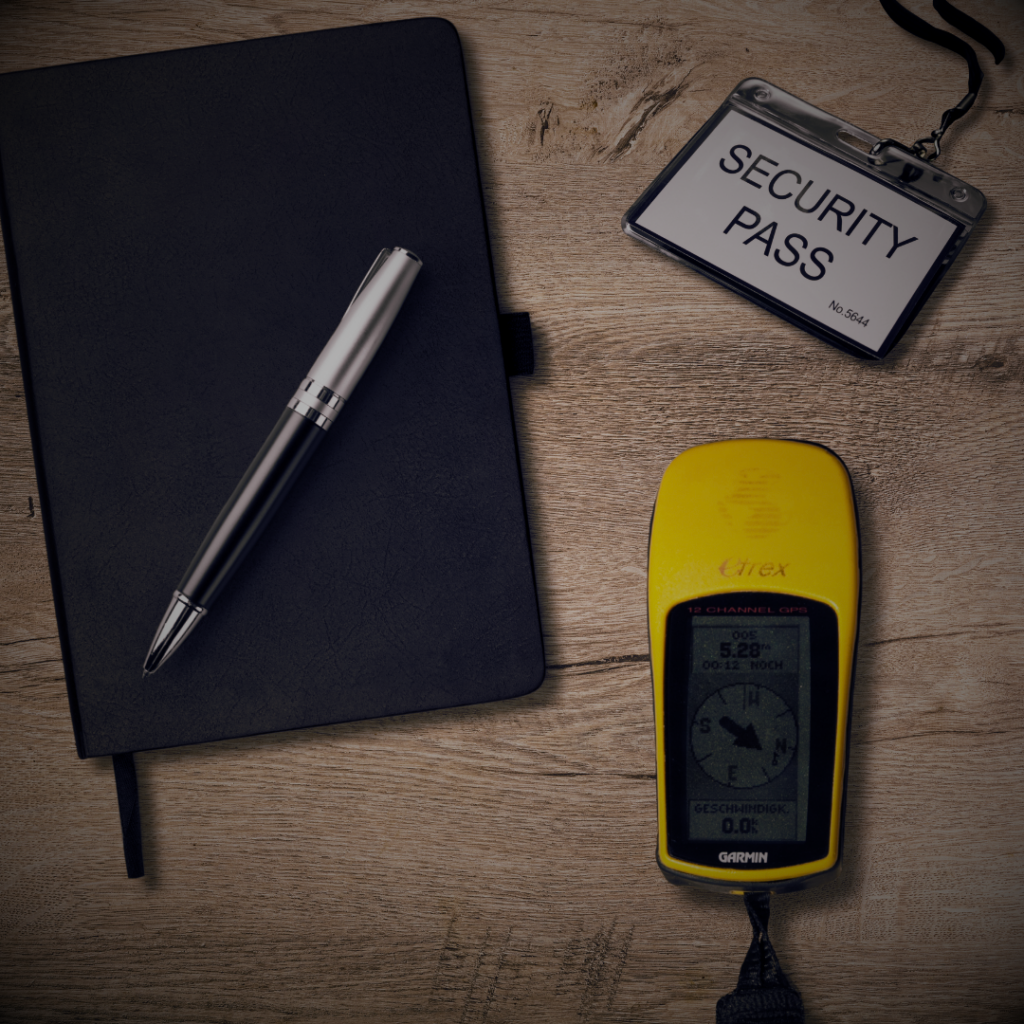 flat lay of notebook, security pass, and gps