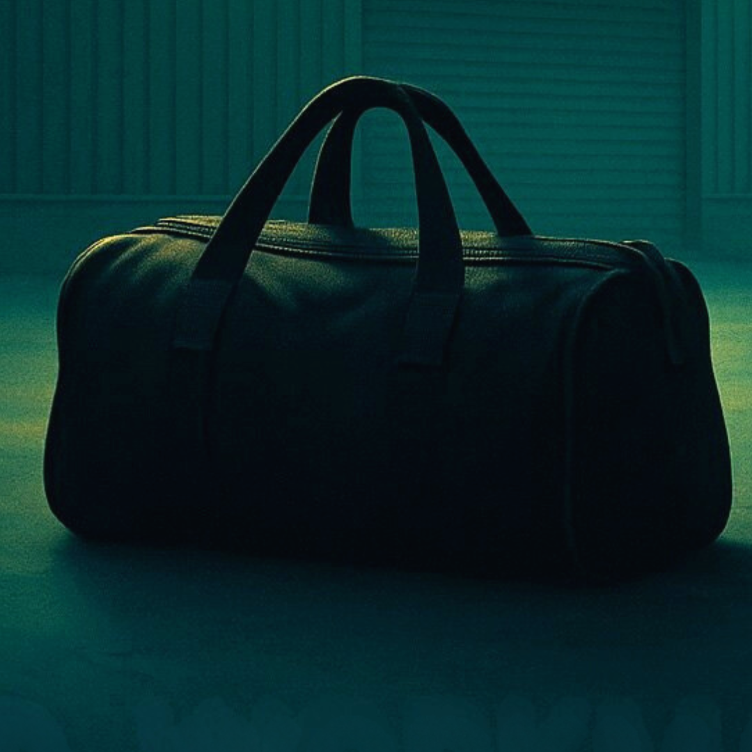 A dark duffel bag sits alone in teal light.